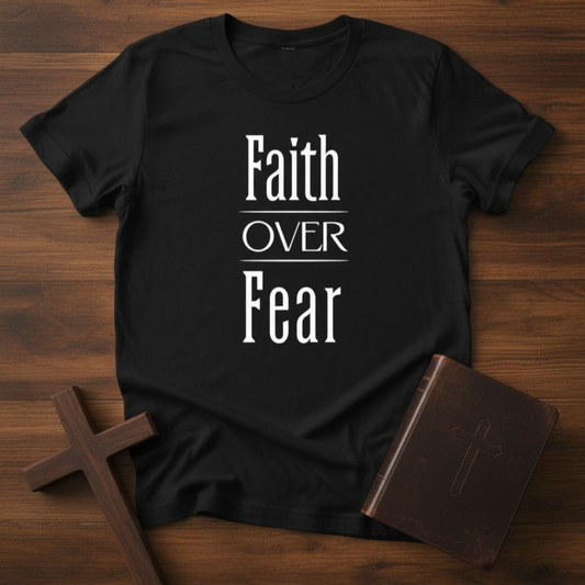 Black t-shirt with 'Faith Over Fear' text on a wooden surface with a cross and book.