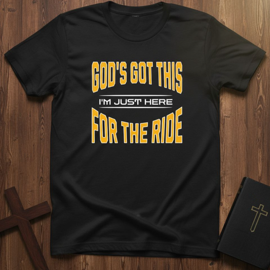 Black t-shirt with yellow text on a wooden surface with a cross and notebook.