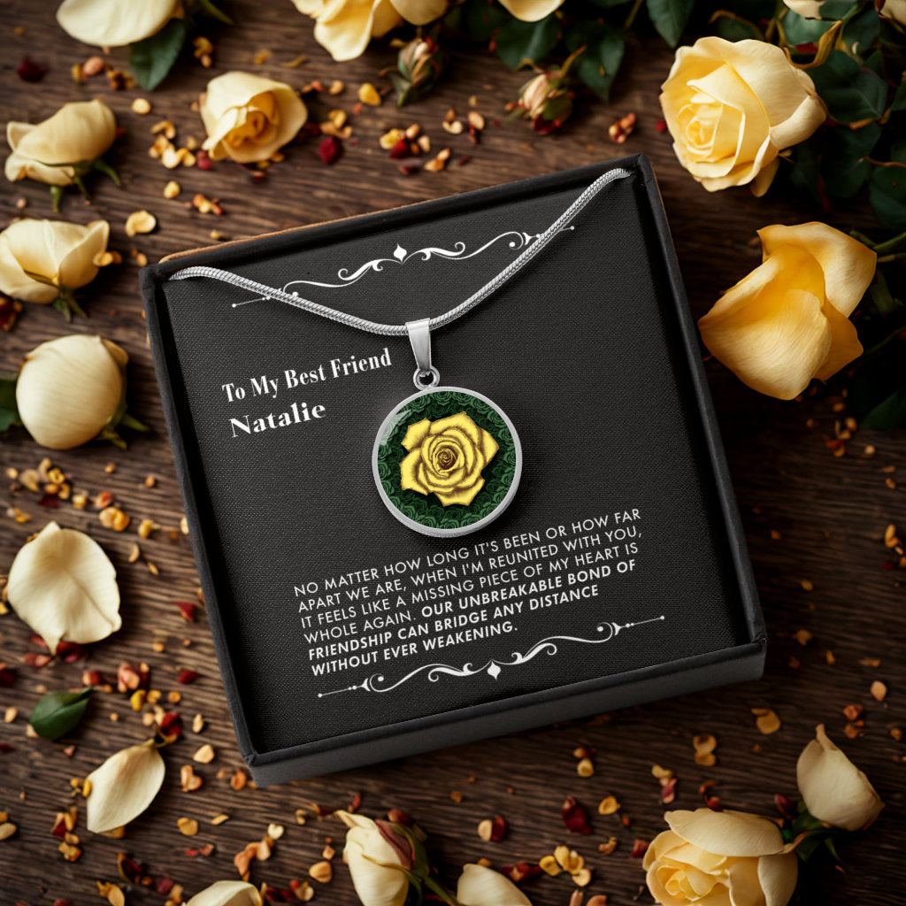 Necklace with a yellow rose pendant in a gift box, surrounded by yellow roses on a wooden surface.